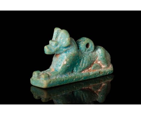 Ca. 664 - 332 BC.A mould-formed faience jackal amulet shown in a recumbent pose. The resting feline is displayed with front p