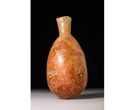 Ca. AD 1 - 100.A glass unguentarium with a piriform lower body and a funnel-shaped neck. The base bears a pontil mark, and th