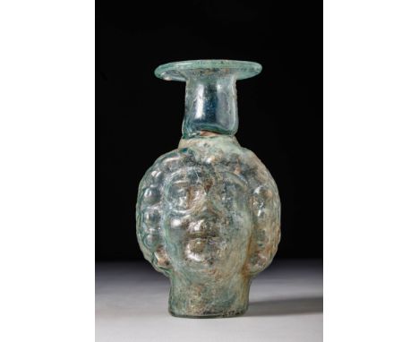 Ca. AD 200 - 300.A glass flask formed in transparent light green glass, mould-blown in two pieces, with a seam visible along 
