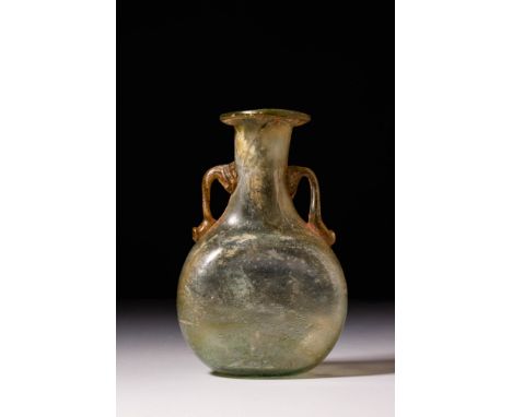 Ca. AD 100 - 300.A Roman free-blown pale green glass vessel that sits on a flat base. The vessel has a slender, tubular neck 