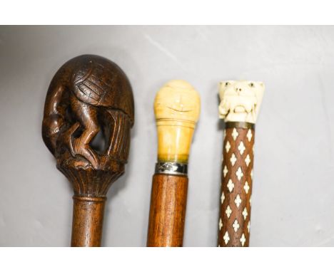 Three various walking canesIncluding two carved Ivory topped walking canes, one the cane in laid with Ivory, and a carved woo