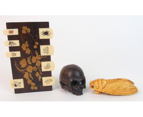 A Japanese carved ivory cicada netsuke signed, 6cm long, hardwood netsuke skull, 4cm wide and a game counter (3)