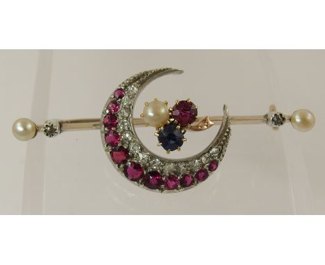 A Victorian crescent moon brooch set with rubies, pearls, diamonds and a sapphire with a central shamrock motif to the centre