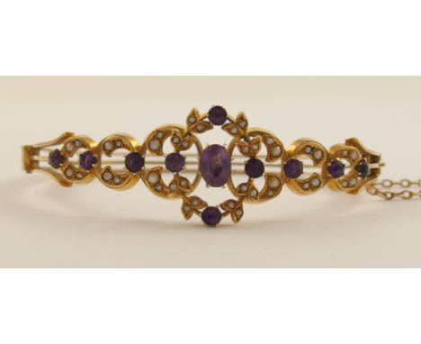 A 15ct gold late Victorian/Edwardian bangle set with amethysts and seed pearls to the floral design front with a three strand