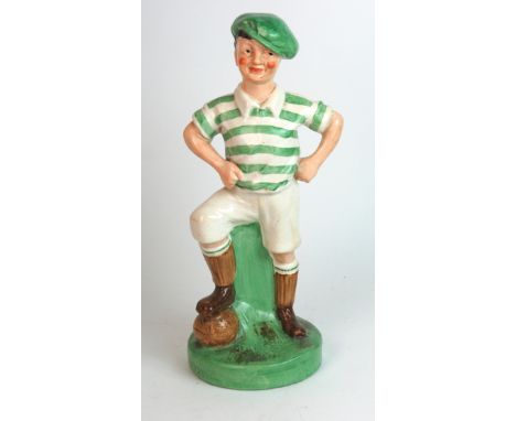 A Britannia Pottery figure of "Wee McGregor" the figure decorated in the colours of Celtic F.C., his foot resting on a footba