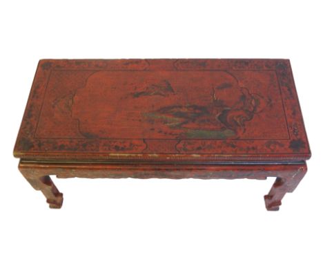 A Chinese red and black lacquered rectangular low table decorated with an extensive landscape with a foliate scroll border an