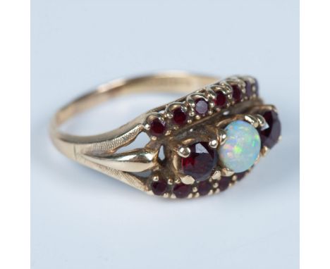 The lovely setting makes this ring quite unique. The center is a cabochon opal with a faceted garnet on either side. The top 