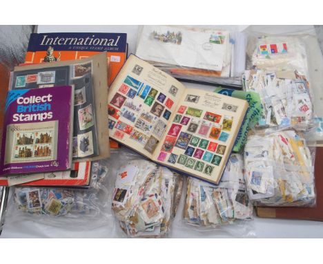 A box containing various stamps albums, including an International Unique Stamp Album, partially filled with a range of Briti