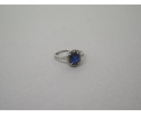 An Art Deco sapphire and diamond ring set in platinum (hallmarked)  the central oval sapphire surrounded by 12 round and twin