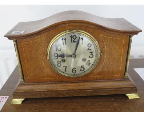 An oak mantle clock with turned pillars and glass front 