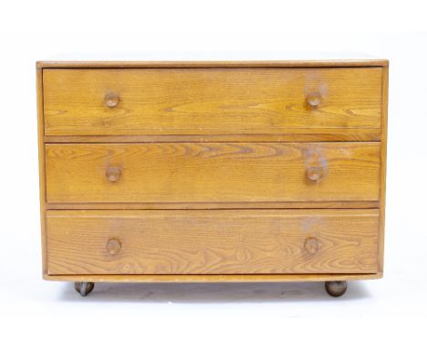 AN ERCOL LIGHT ELM CHEST of three drawers 91cm wide x 48cm deep x 66cm high, a small Ercol chair and a cane back open armchai
