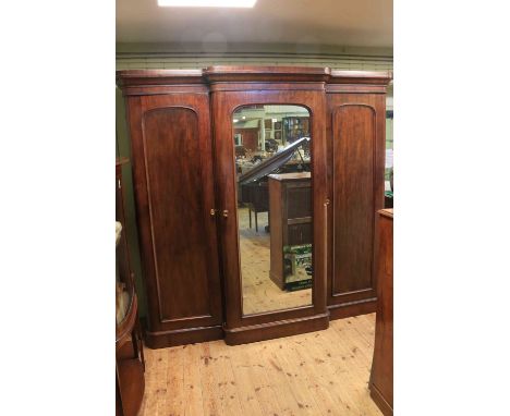 Victorian mahogany breakfront wardrobe, the central mirror panel door enclosing four sliding trays and three drawers, flanked