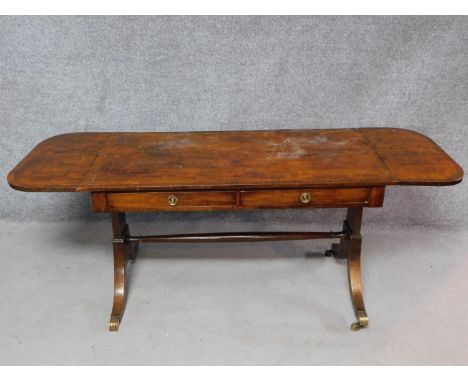 A late 19th century mahogany Regency style sofa table on swept supports terminating in reeded brass cap casters. H.68 W.178 D