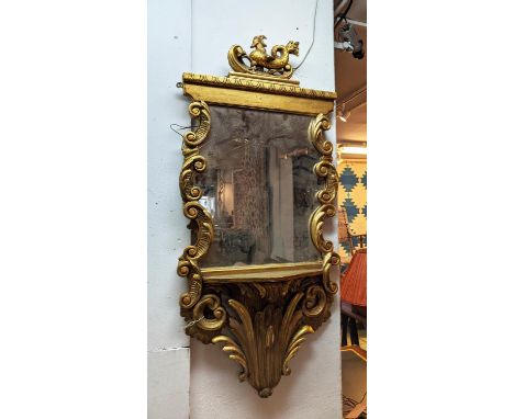 WALL MIRROR, 127cm H x 60cm, 19th century continental giltwood with a decorative surmount, scrolled detail and a shelf. 