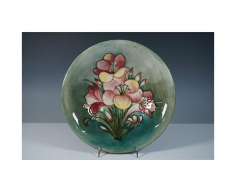 A Moorcroft pottery bowl featuring a delicate display of African lilies in full bloom. The floral design showcases petals in 