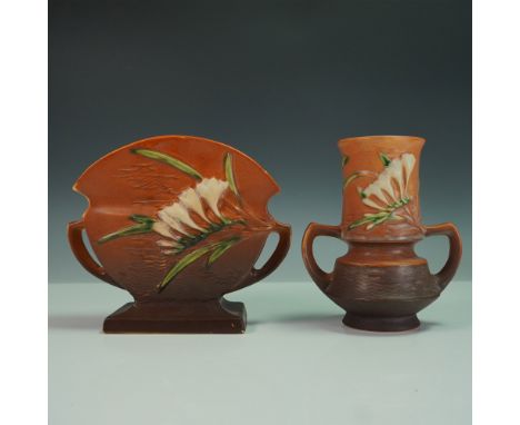 Two Roseville Pottery vases in the Freesia pattern, featuring sculptural white and yellow freesia blooms with green foliage a