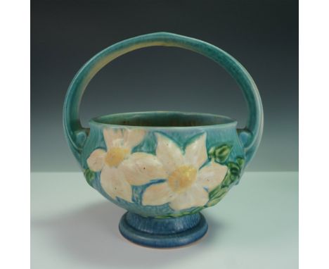 This vintage Roseville Pottery basket bowl from the Clematis line features raised white blossoms with yellow centers and trai