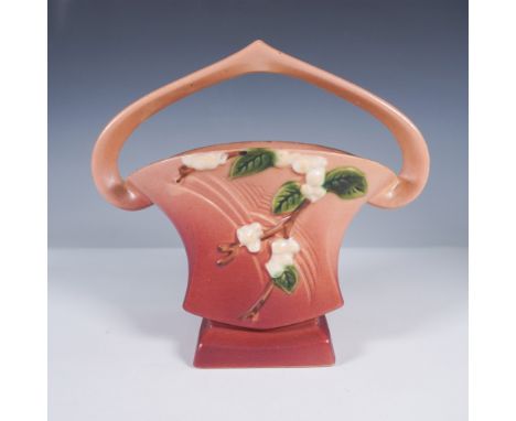 Crafted by Roseville Pottery, this Snowberry line basket vase, marked IBK-7, features a sculptural looped handle and elegantl