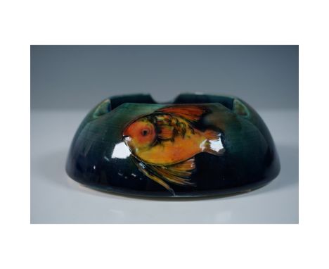 A rare Moorcroft pottery ashtray featuring a striking depiction of a goldfish against a green and blue gradient ground. Desig
