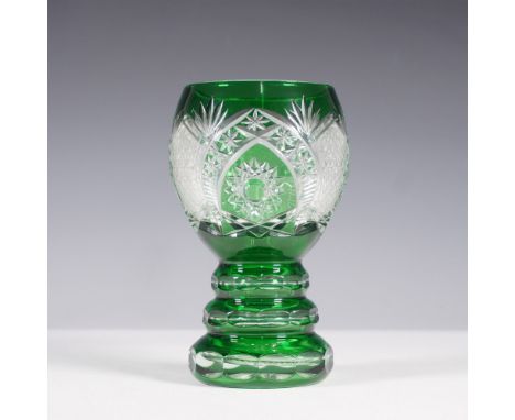 A striking Bohemian cut-to-clear crystal goblet in vibrant emerald green, showcasing intricate geometric and floral patterns 