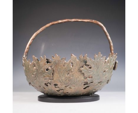 Exquisitely crafted bronze basket featuring an intricate openwork leaf motif. The detailed design showcases overlapping oak l