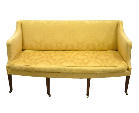 An Edwardian three seater sofa, bow fronted on four mahogany square section tapered front legs, on brass casters, upholstered