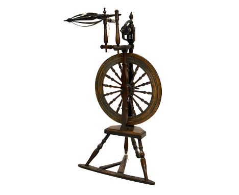 A 19th century fruitwood and beech spinning wheel, bobbin turned with dowelled and pegged attachments, 106cm high