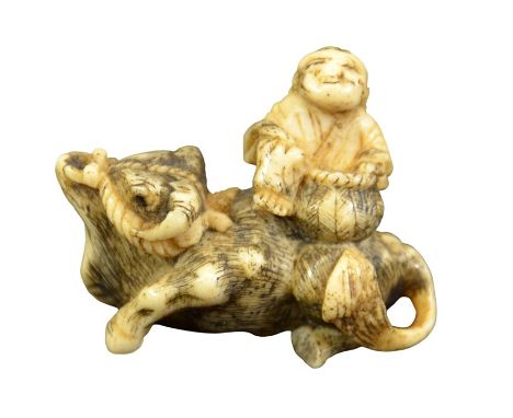 A 19th century Japanese carved bone netsuke, Meiji, modelled as a man on a water buffalo, 5cm long