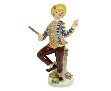 A Meissen porcelain Comedia Dell'Arte figure of Harlequin, after J J Kandler, 20th century, modelled by a tree stump holding 