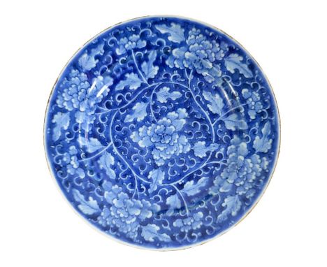 A Chinese blue and white plate, Kangxi, circa 1700, painted with lotus flowers in a foliate scroll ground, 21.5cm diameter