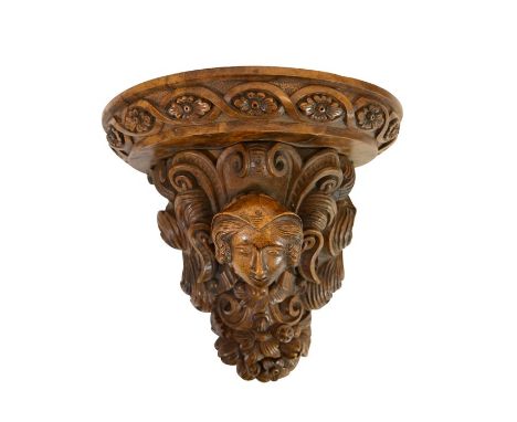 A 19th century cared walnut wall bracket, French, Henri II style, with face and fruiting foliage