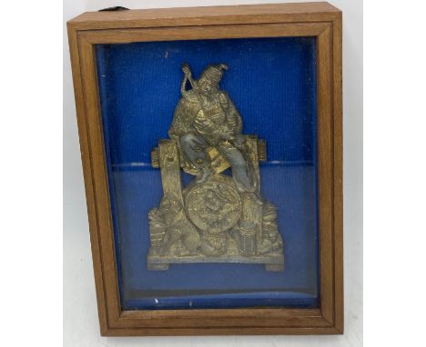 A  framed 19th century gilt metal stand with central plaque, cast as a Scottish Highlander, seated with bagpipes, his ale, pi