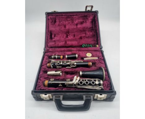 A clarinet by Corton by Amati in a case, with a collection of clarinet music books.