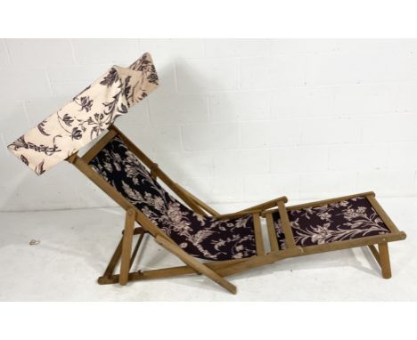 A folding teak steamer chair with sun canopy and footstool finished with Laura Ashley material
