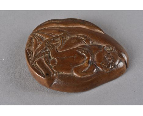 A Meiji period Japanese wood manju netsuke, of pear shape with relief carving of a monkey seated within foliage, signed indis