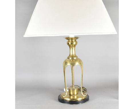 A Middle Eastern style table lamp, the brass triform lower section on circular base and ebonised plinth supporting a vase top