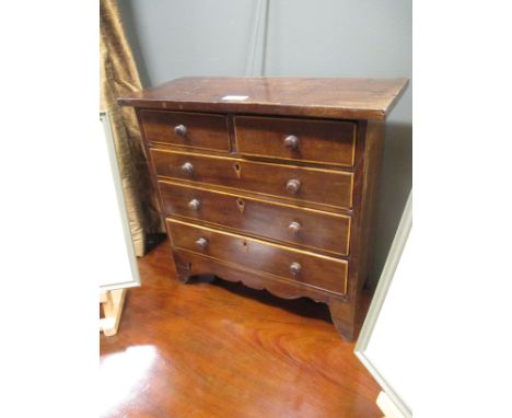 A George IV mahogany apprentice or miniature chest of drawers, the two short and three long graduated drawers inlaid with box