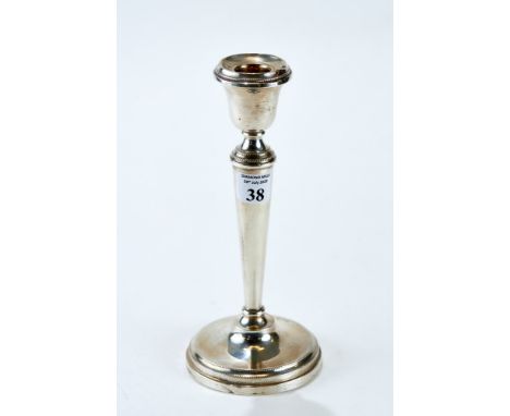 A GEORGE V SILVER TABLE CANDLESTICK raised on a circular beaded border base, maker: M. J., Birmingham 1930, loaded, 8" high. 