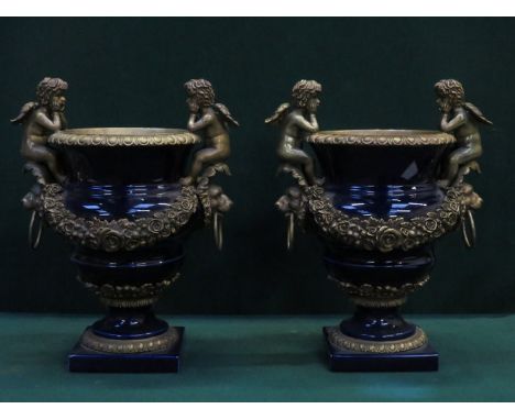 PAIR OF FRENCH STYLE GILT METAL AND CERAMIC URNS DECORATED WITH CHERUBS 