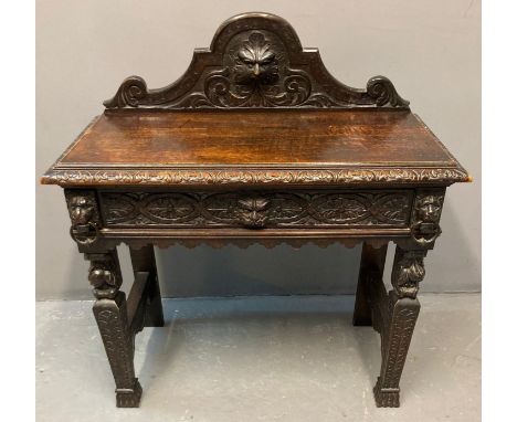 Victorian oak ornately carved side table, the shaped gallery back with carved mask head above a moulded top with carved friez