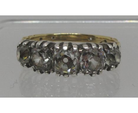 Diamond five stone ring set in white metal with yellow metal band. Of three old cushion cut and two old cut diamonds. Ring si