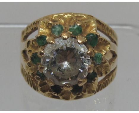 18ct gold flower ring set with a large white stone surrounded by emeralds.  Ring size O.  Approx weight 7.2 grams.(B.P. 21% +