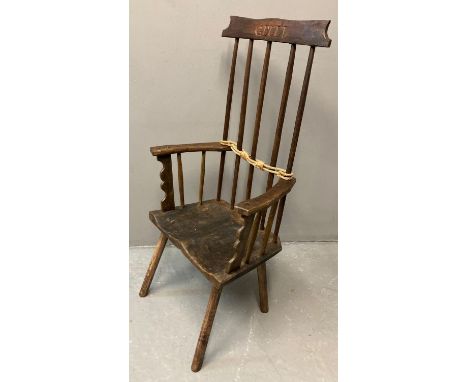 Primitive design stick back armchair on moulded saddle seat, carved 'Gelli'.  111cm high approx.   (B.P. 21% + VAT) 