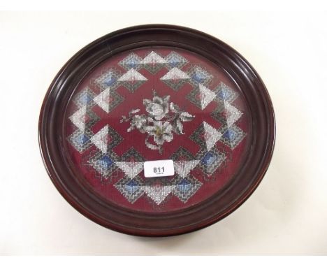 A beadwork floral panel in mahogany circular tray surround