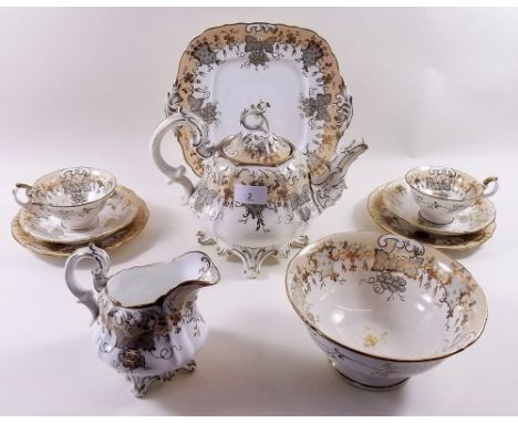 A Victorian Rockingham style tea service in gilt and white comprising cake plate, teapot, milk jug, large bowl, six tea plate