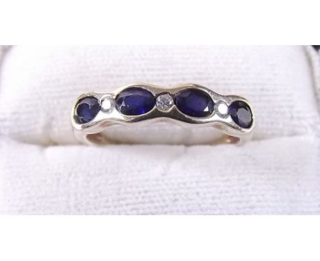 A 9 carat gold ring set four oval cut sapphires and three chip diamonds
