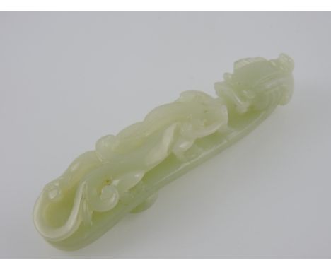A Chinese green jade belt buckle in the form of a dragon. L 11cm
