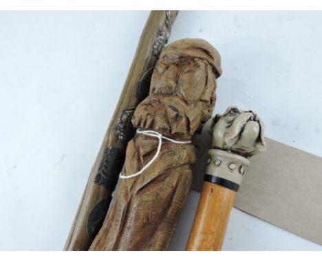 A walking stick, the top crudely carved as a bearded gentleman, L. 79cm, together with two other similar examples, one topped