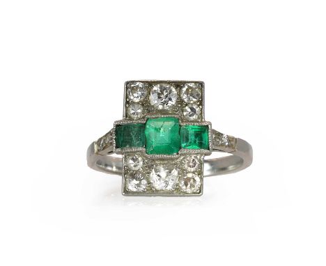 An emerald and diamond panel ring, c.1915,  with three square faceted emeralds, surrounded by old cut diamonds, in a panel de