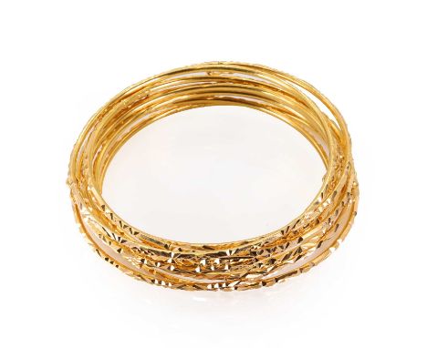 A group of nine plain gold bangles, with similar but different engraved designs and opening with a safety catch, each bangle 